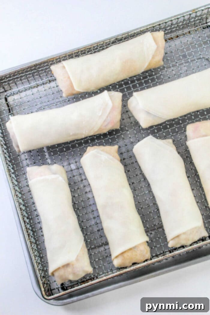 A stack of perfectly rolled homemade spring rolls ready for air frying.