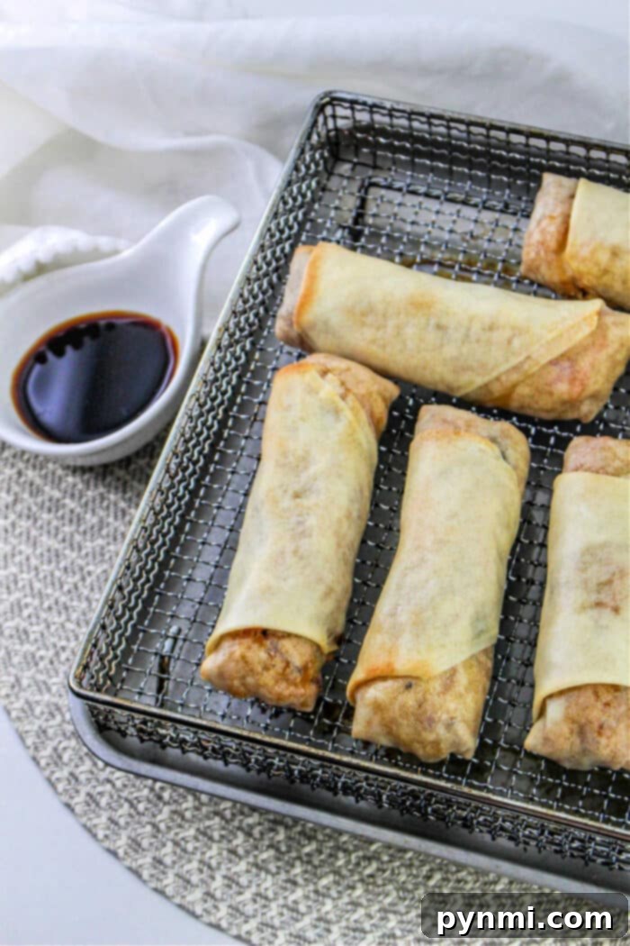 Delicious spring rolls cooking in an air fryer basket, showing a golden brown finish.