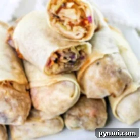 A stack of air fryer spring rolls filled with vegetables sits enticingly on a white plate, showcasing a perfect blend of crispiness and flavor.