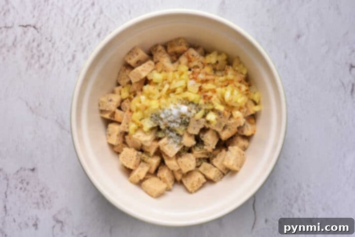 Golden Sourdough Croutons 5 A bowl of freshly made cornbread croutons, golden brown and perfectly cubed, ready to be added to a dish. The texture shows a light crispness, and crumbs are visible around the base of the bowl, suggesting a homemade quality.