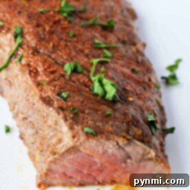 Grilled steak, reminiscent of how to cook tri-tip in the oven, is seasoned with herbs and spices, garnished with parsley, on a white plate.