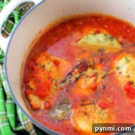 Enjoy a hot braised chicken stew with tomatoes, herbs, and spices simmering in a white pot.