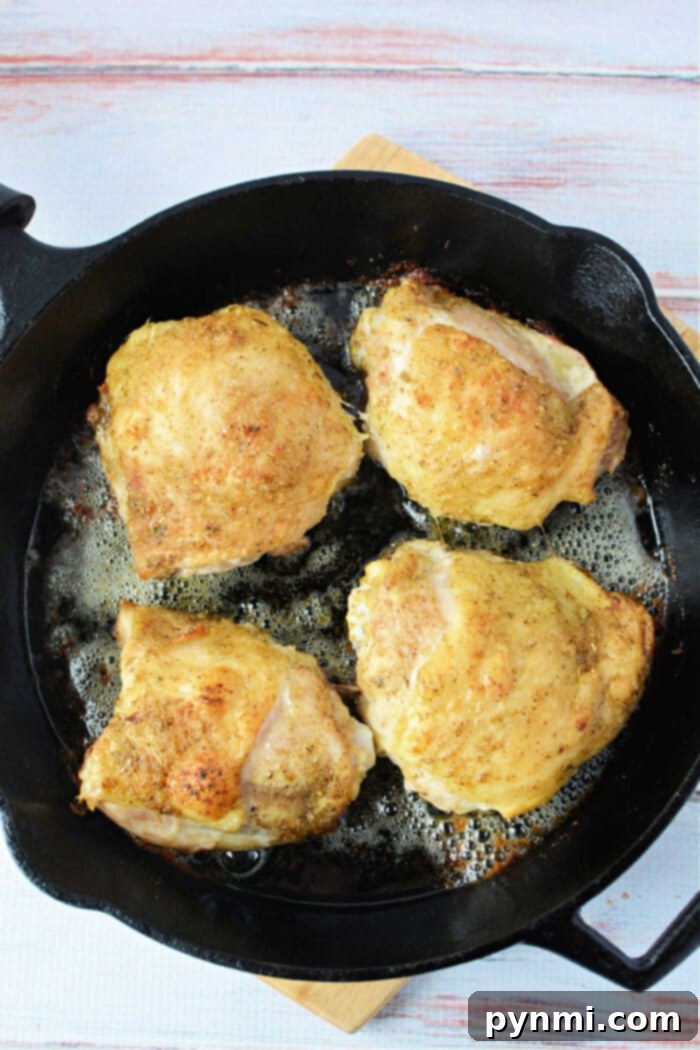 Crispy Skinned, Juicy Bone-In Chicken Thighs 5 A cluster of seasoned bone-in chicken thighs, perfectly baked in the oven, showcased to demonstrate ideal doneness.
