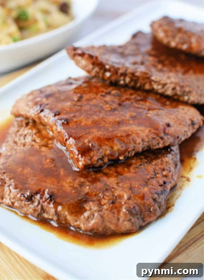 Juicy, cooked cube steak slices with sauce on a white plate, highlighting the tender outcome of perfectly pan-fried cube steak.