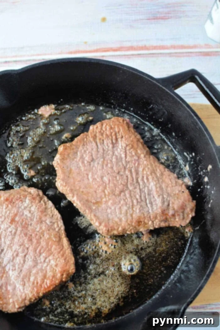 Close-up of a perfectly seared cube steak in a cast iron pan, ready to be served, emphasizing the quick cooking time.