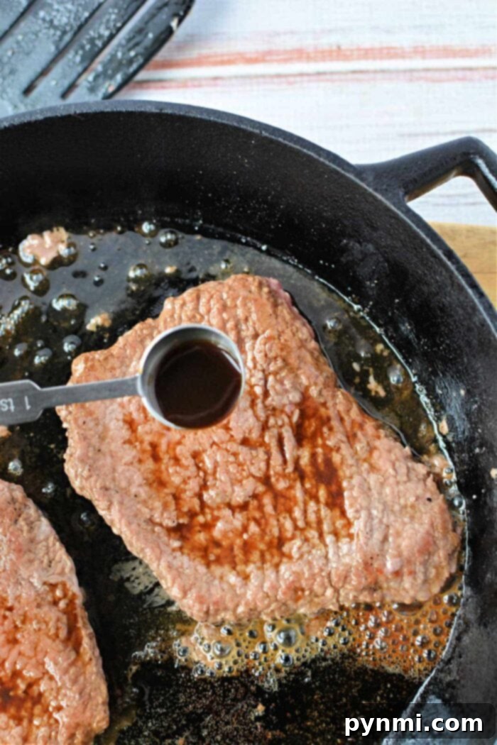 Tender cube steak recipes on stove. Cooked cube steak slices on a plate with gravy, demonstrating the perfect tenderness achieved on the stove.