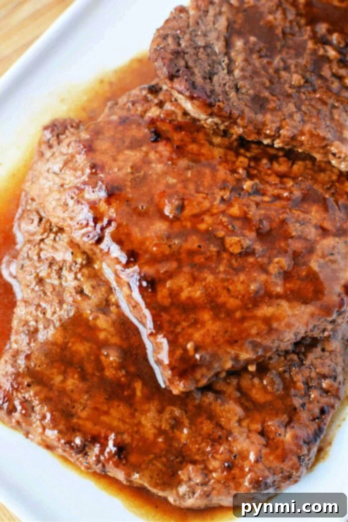Close-up of juicy, cooked cubed steaks smothered in rich brown gravy on a white plate, showcasing the tenderness and flavor achieved through careful cooking.