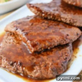 Juicy, cooked cube steak slices with sauce on a white plate, illustrating the perfect tenderness from pan frying.