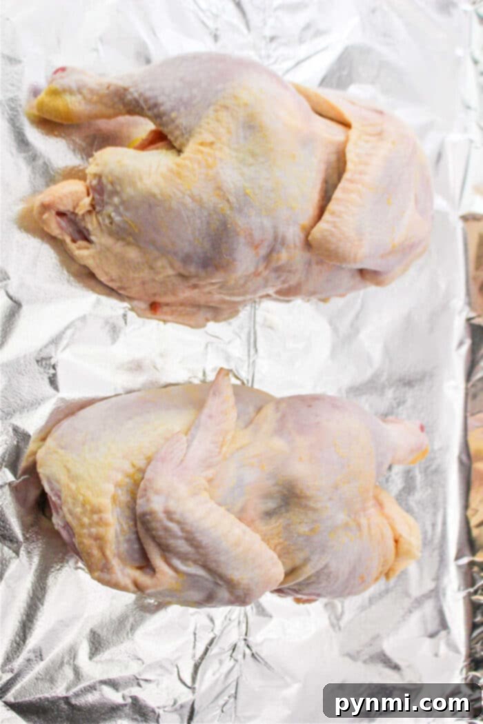 Perfect Half Chicken: Roasting Time at 400F 4 Two raw half chickens rest on aluminum foil, ready for preparation and seasoning.