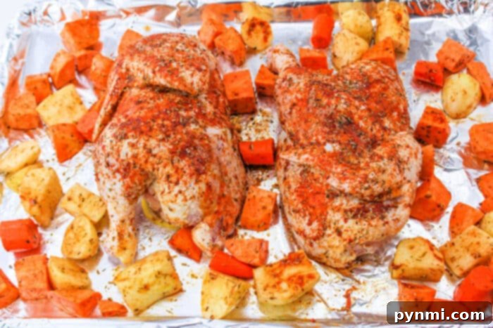 Perfect Half Chicken: Roasting Time at 400F 8 A seasoned half chicken rests amid chunks of sweet potatoes and carrots on a foil-lined baking sheet, ready for the oven.
