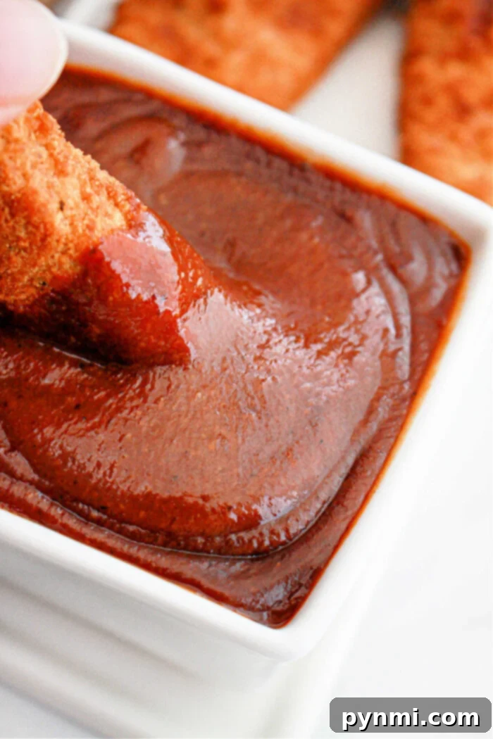 Crafting Popeyes Iconic Sauce 2 Crispy chicken being dipped into a rich, homemade Popeyes-style barbecue sauce in a white bowl, inviting and delicious