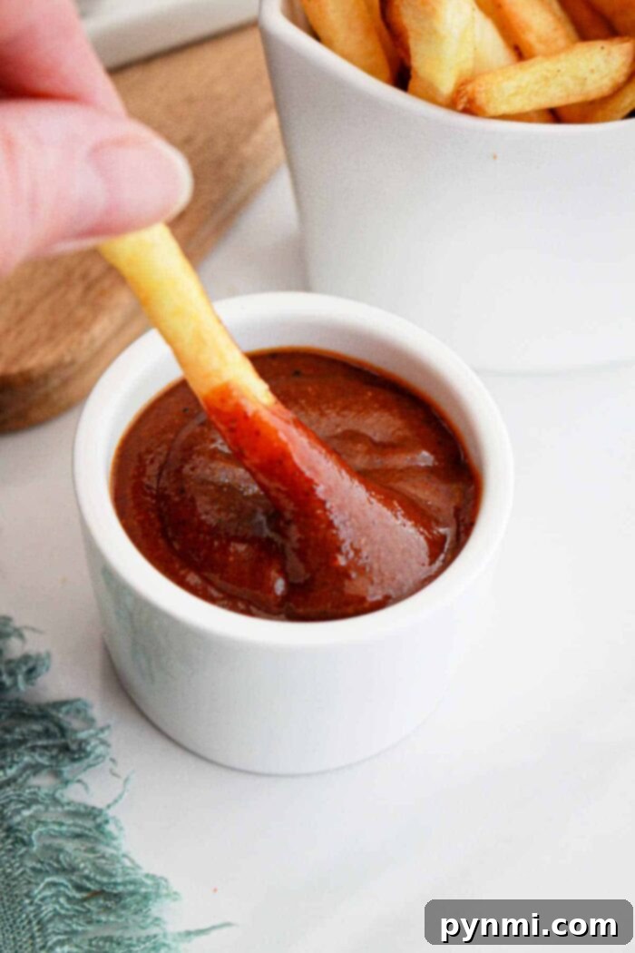 Crafting Popeyes Iconic Sauce 6 A generous dollop of rich, dark copycat Popeyes BBQ sauce in a small ceramic bowl, ready to be enjoyed