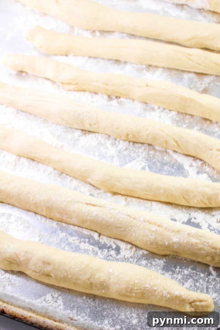 Adorable Easter Bunny Bread 7 Raw breadsticks, reminiscent of a classic Bunny Bread recipe, are arranged on a floured baking sheet.