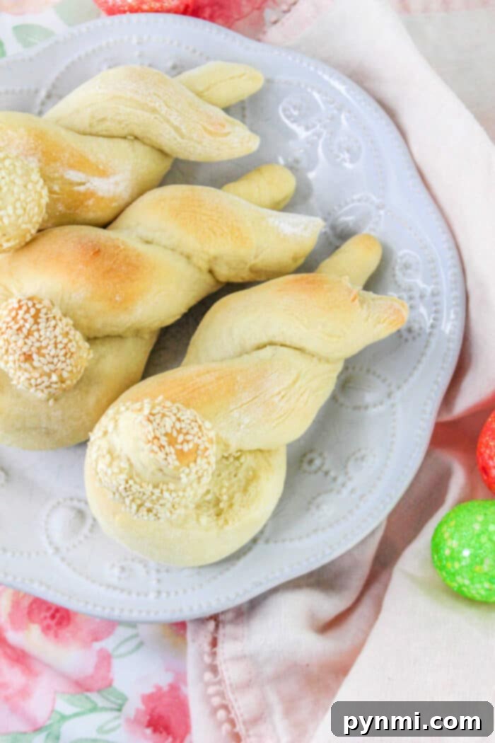 Adorable Easter Bunny Bread 9 Twisted breadsticks with sesame seeds on a white plate, surrounded by colorful eggs and a floral tablecloth, offer a festive touch to your Bunny Bread recipe presentation.