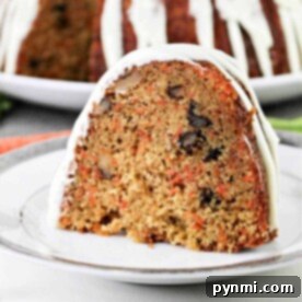 A slice of carrot pound cake with nuts and white icing graces the plate, while the whole cake sits enticingly in the background.