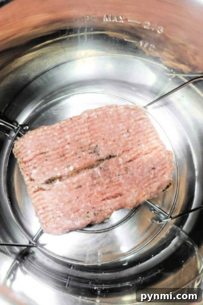 Ground chicken on a metal trivet inside an Instant Pot, ready for cooking, promising a quick and even cook for meal prep.