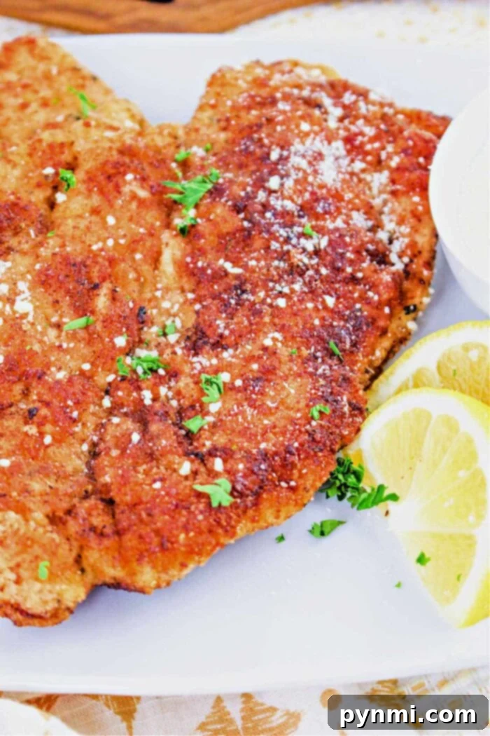 The Best Baking Time for Chicken Cutlets 2 A close-up of golden brown breaded baked chicken cutlets, garnished with fresh herbs and served alongside zesty lemon slices on a pristine white plate, promising a juicy and tender bite.