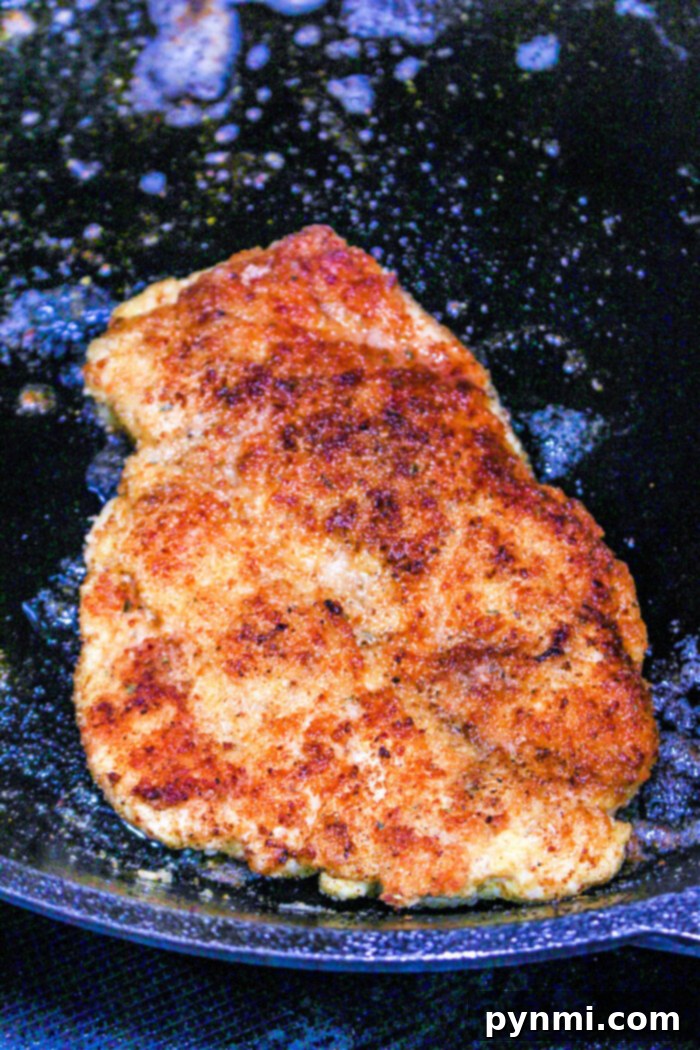 The Best Baking Time for Chicken Cutlets 5 Golden brown breaded chicken frying in a black pan with oil bubbling around it, offering a mouthwatering aroma that's hard to resist. While frying creates that crisp crust, for those wondering how long to bake chicken cutlets instead, the oven method ensures juicy tenderness inside.
