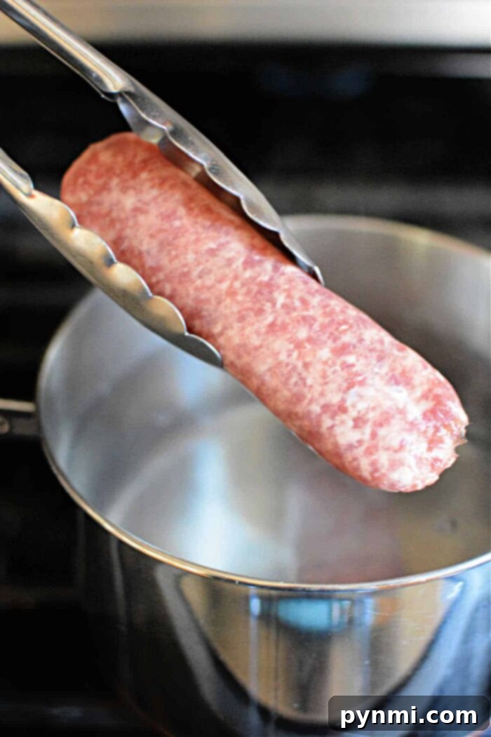 Tongs holding raw brats over a pot of boiling water on the stove, as you ponder how long to boil brats for that perfect flavor.