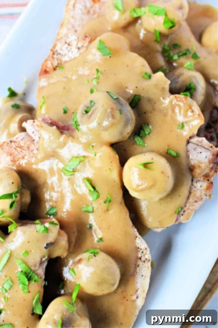 Skillet Pork Chops with Savory Mushroom Gravy 2 Perfectly Cooked Pork Chops with Mushroom Gravy, garnished with fresh herbs