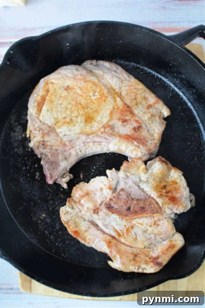 Skillet Pork Chops with Savory Mushroom Gravy 6 Golden brown pork chops nestled in a creamy mushroom sauce, served on a dinner plate