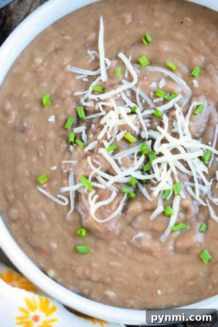 Elevate Your Canned Refried Beans 4 A vibrant bowl of expertly prepared refried beans, garnished with fresh cilantro and a dollop of sour cream, showcasing the delicious transformation of canned refried beans into a gourmet dish.
