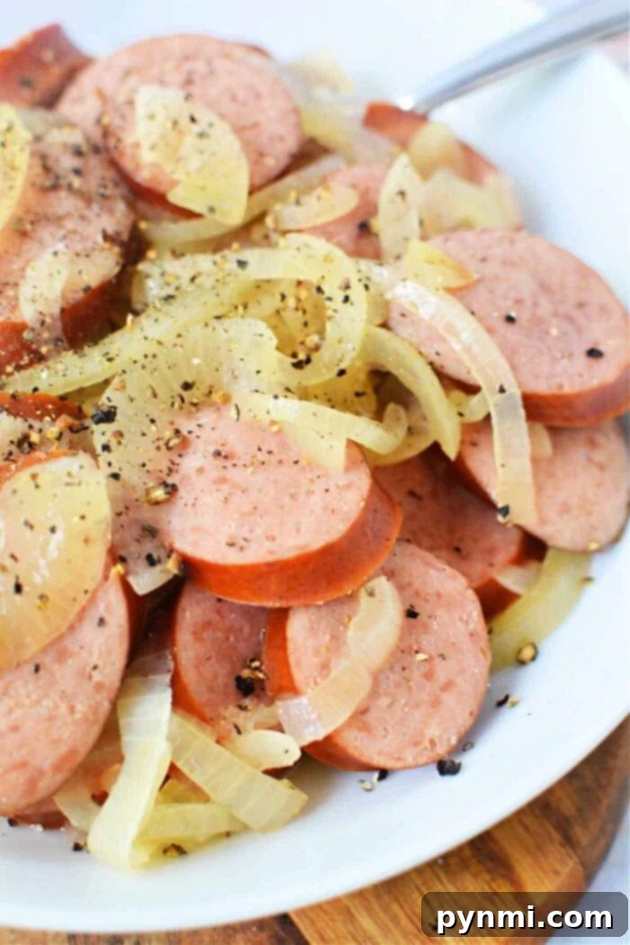 Recipe for Kielbasa in Crock Pot with sliced onions and a beer in the background