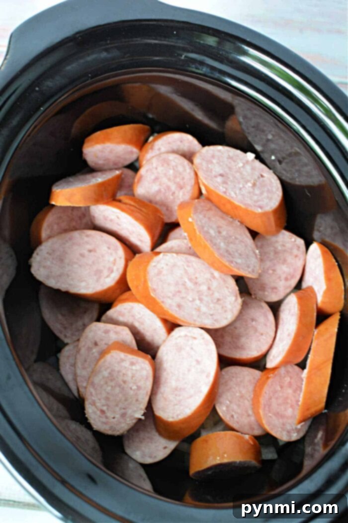 Kielbasa in Crock Pot with onions and beer, ready to be slow-cooked for hours