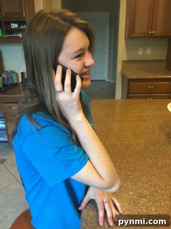 A tween happily showing her new Walmart Family Mobile phone, symbolizing the joy and responsibility of a first device.