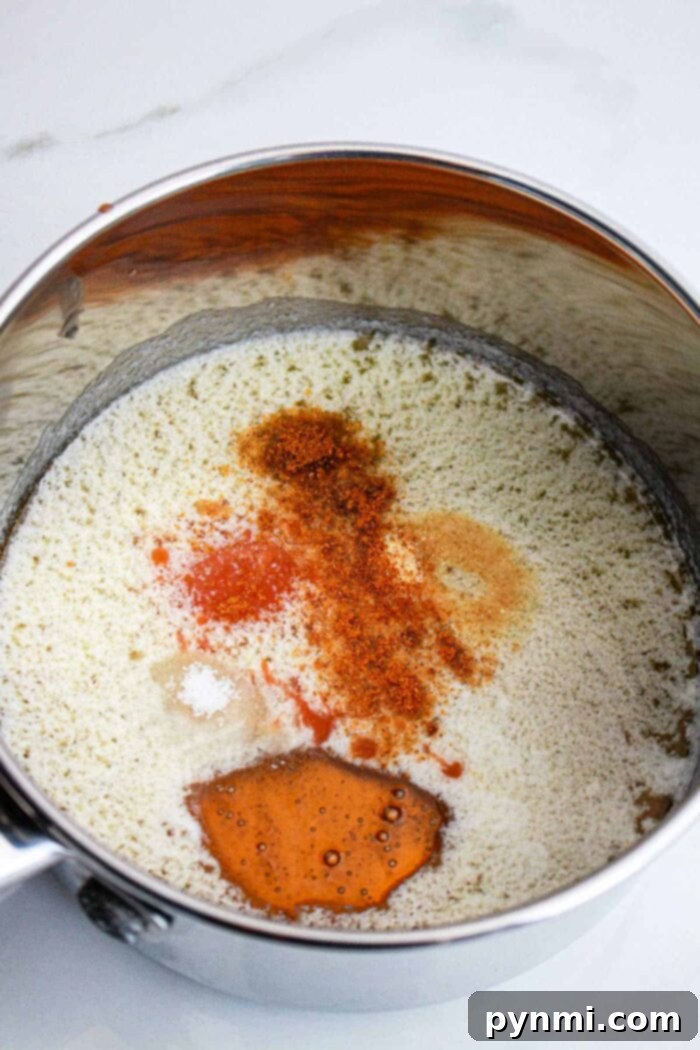 Sweet Heat Perfection: Crafting Homemade Hot Honey 5 Finished hot honey sauce in a glass jar, with a honey dipper, ready to be served, highlighting its rich color and inviting texture.
