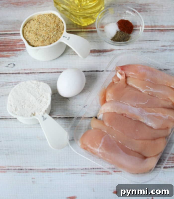 How to bread chicken tenders - A close-up of perfectly breaded raw chicken tenders on a plate.