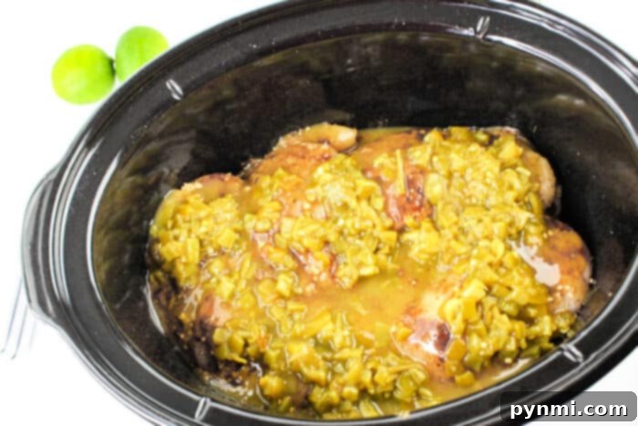 Zesty Green Chili Slow Cooker Chicken 6 Crockpot chicken breasts topped with green chili sauce, two limes nearby, brings a burst of citrus flavor.
