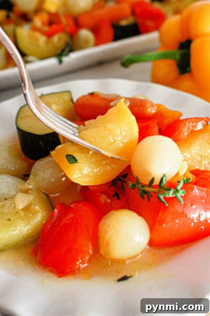 A close-up of a plate with cooked vegetables, including cherry tomatoes, onions, and slices of zucchini. A fork is picking up a piece of yellow pepper. A yellow bell pepper and more slow cooker vegetables are visible in the background.