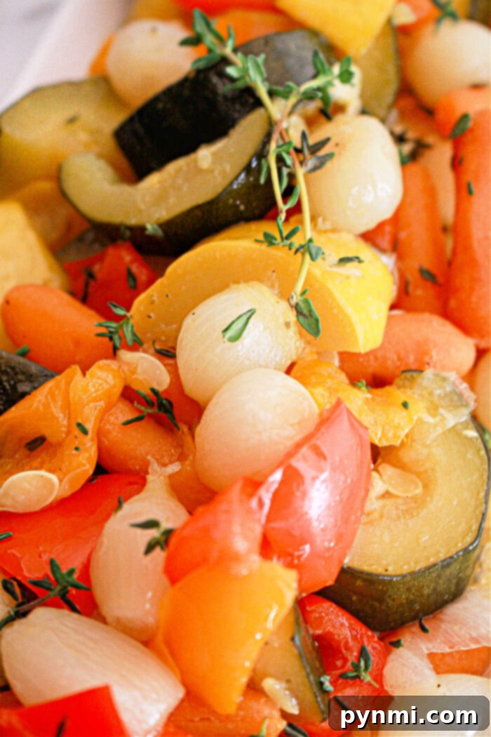 A close-up of a mixed vegetable medley featuring zucchini slices, baby carrots, pearl onions, and bell pepper pieces, garnished with sprigs of thyme. The Slow Cooker Vegetables appear to be cooked and seasoned, displaying vibrant colors.
