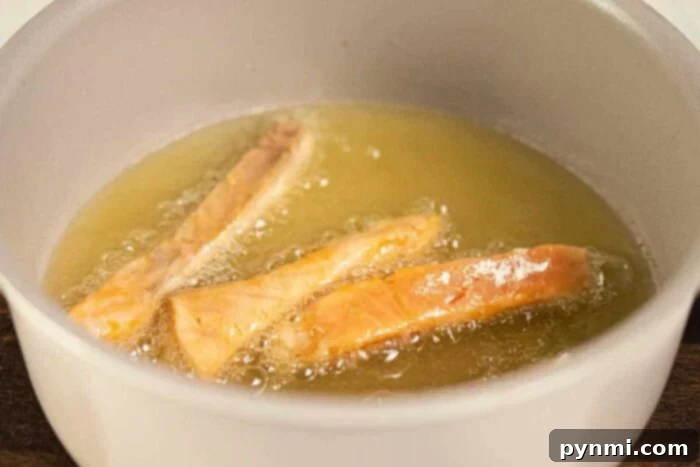 Crispy Floured Salmon 5 Salmon pieces being deep fried in a pot on the stove, bubbling in hot oil