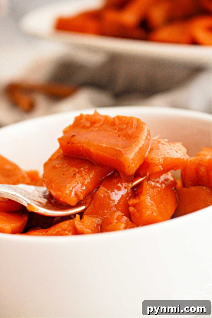 Crock-Pot Caramelized Sweet Potato Delight 5 A bowl of homemade candied sweet potatoes, garnished with fresh herbs, showcasing their rich color and glossy sauce.