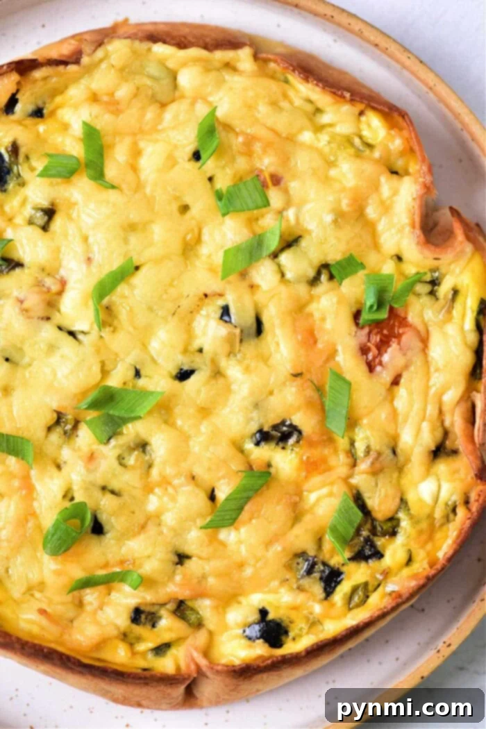 Light and Creamy Cottage Cheese Quiche 2 A vibrant and golden-brown cottage cheese quiche with a tortilla crust, topped with melted cheese and fresh herbs, served on a plate, ready to eat.