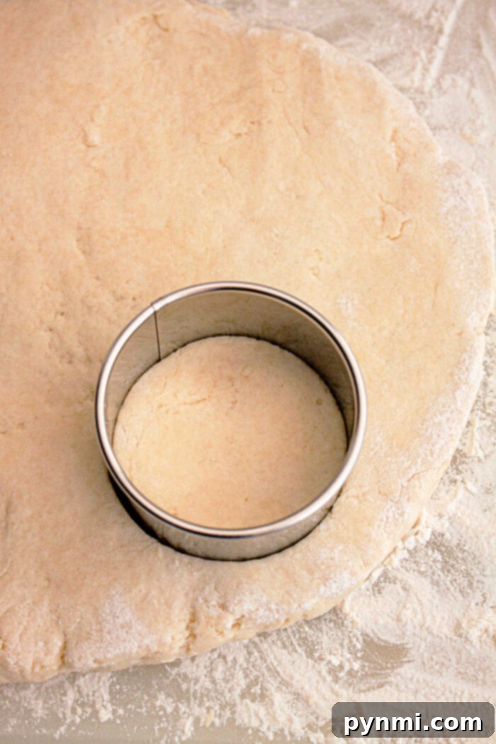 Set-It-and-Forget-It Biscuits and Gravy 5 A metal round cookie cutter pressed into rolled-out dough on a lightly floured surface, perfectly shaping biscuits for Slow Cooker Biscuits and Gravy.