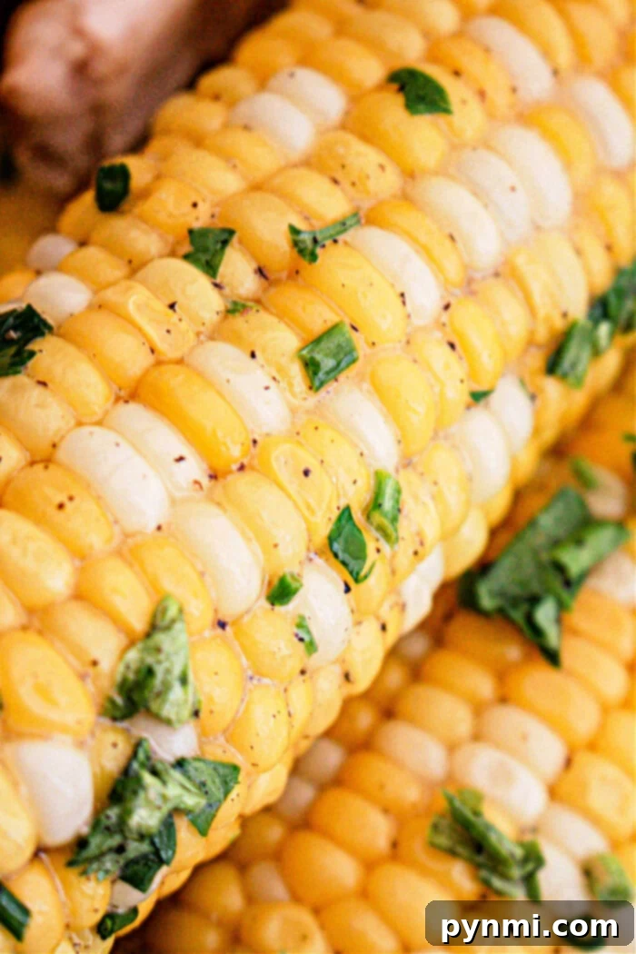 Tender Slow Cooker Corn Perfection 7 Close-up image of Crockpot Corn on the Cob sprinkled with fresh chopped parsley or cilantro. The corn kernels are alternating yellow and white, showcasing a vibrant and delicious dish.