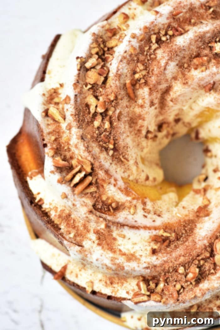 An irresistible overhead shot of a freshly baked Sock It To Me Bundt Cake, generously coated with a creamy white icing, sprinkled with crushed nuts, and dusted with a hint of cocoa powder, inviting a delightful dessert experience.