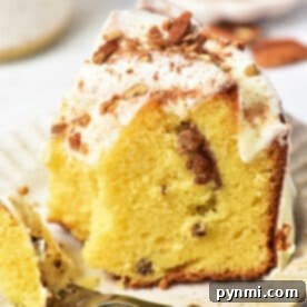 A slice of Sock it to me cake, made with a delightful cake mix, sits on a plate with frosting and nuts, accompanied by a fork.