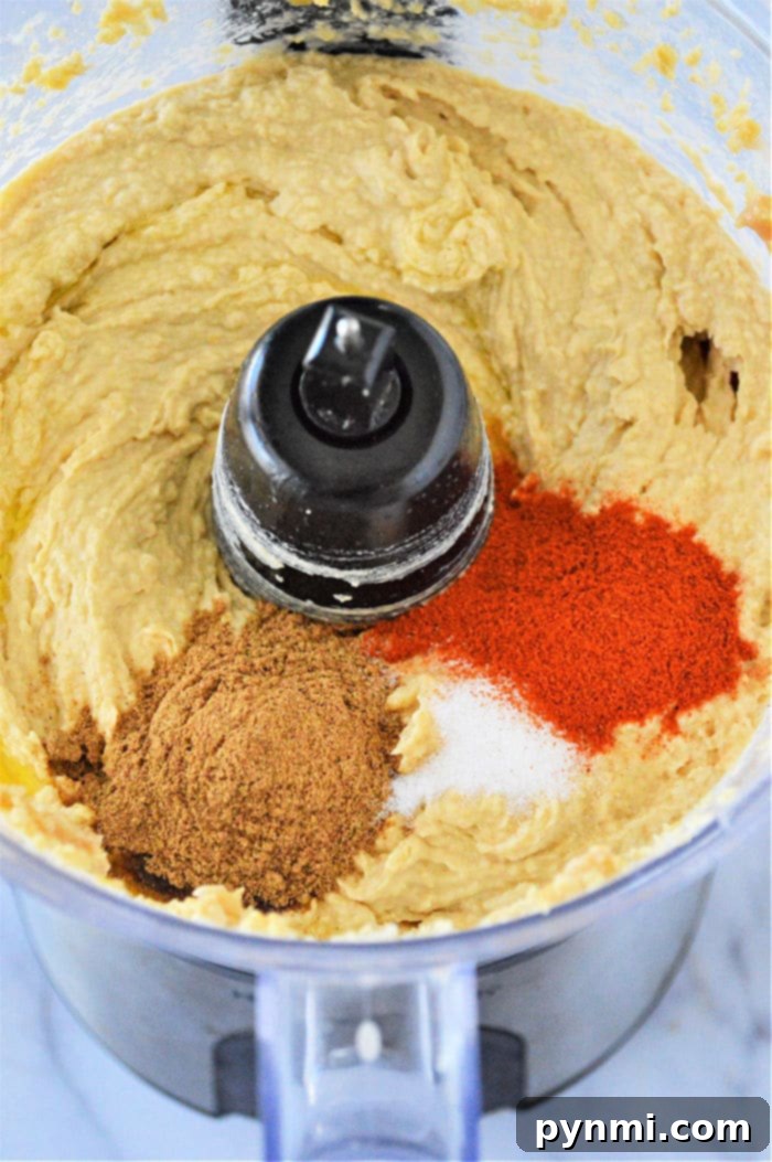 Close-up of a bowl of rich garlic hummus, topped with olive oil and a few sprigs of fresh parsley, ready to be served.