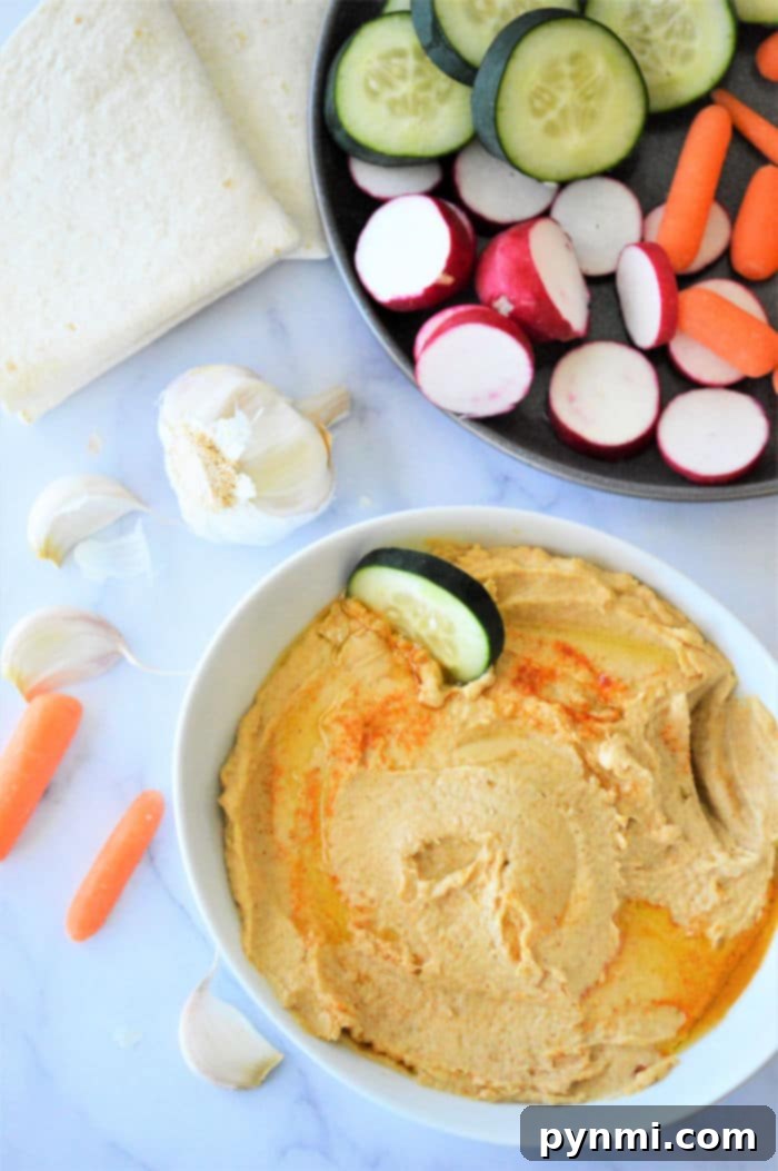 Close-up of creamy homemade hummus garnished with olive oil and paprika, showcasing its smooth texture.