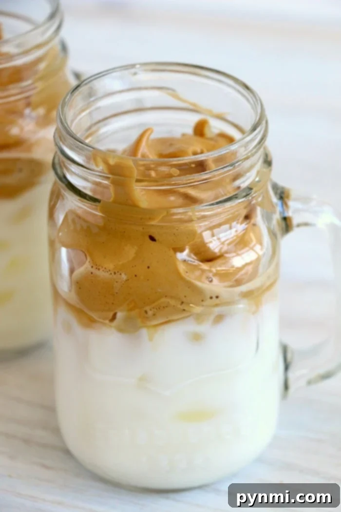 Dalgona whipped coffee, a popular frothy coffee drink, in a tall glass