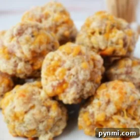 A plate of freshly baked sausage balls with melted cheese, made from biscuit mix, neatly piled on a pristine white dish.