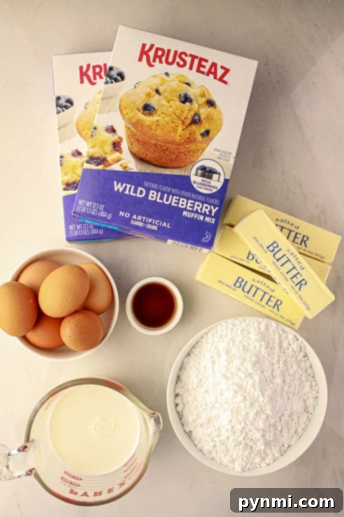 Easy Blueberry Muffin Cake 3 A collection of essential ingredients for transforming muffin mix into a cake, including a box of blueberry muffin mix, fresh eggs, creamy milk, melted butter, and a scattering of fresh blueberries, arranged on a light countertop.