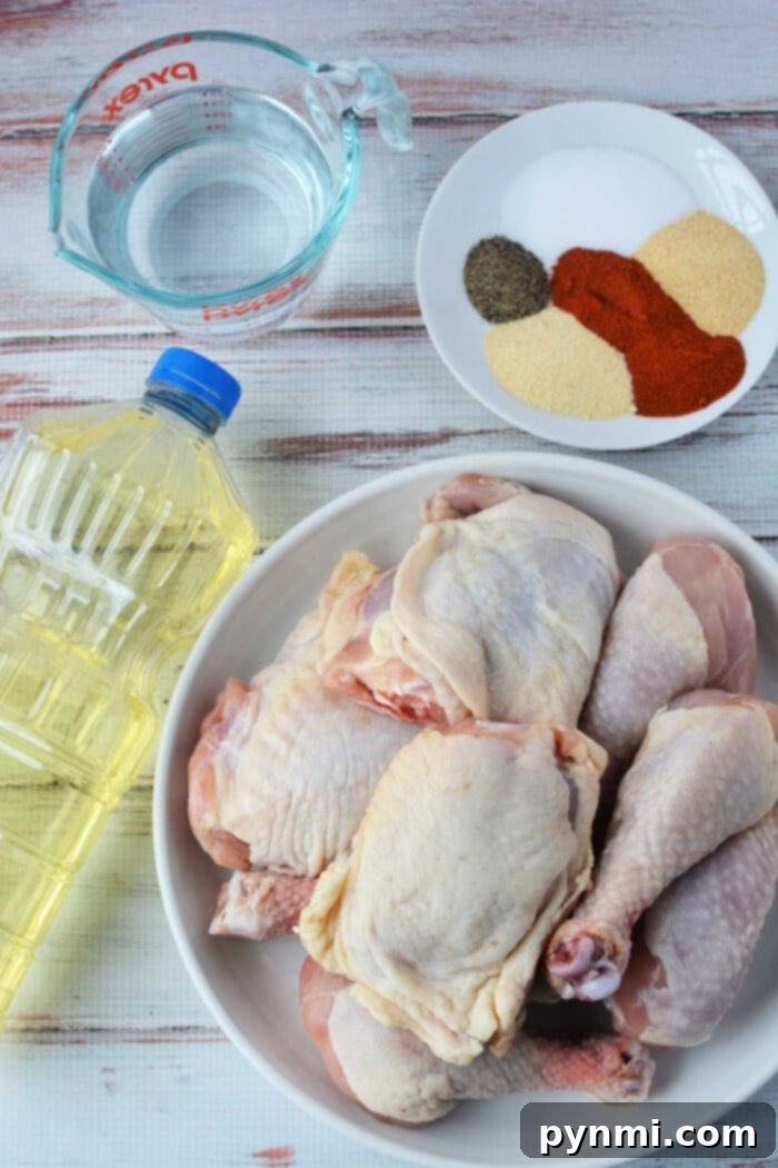A raw chicken awaits transformation beside an oil bottle and a measuring cup of water, with a plate of spices ready to spice things up. Perfect ingredients for pressure cooker magic or crispy fried chicken bliss, all resting on a light wood surface.