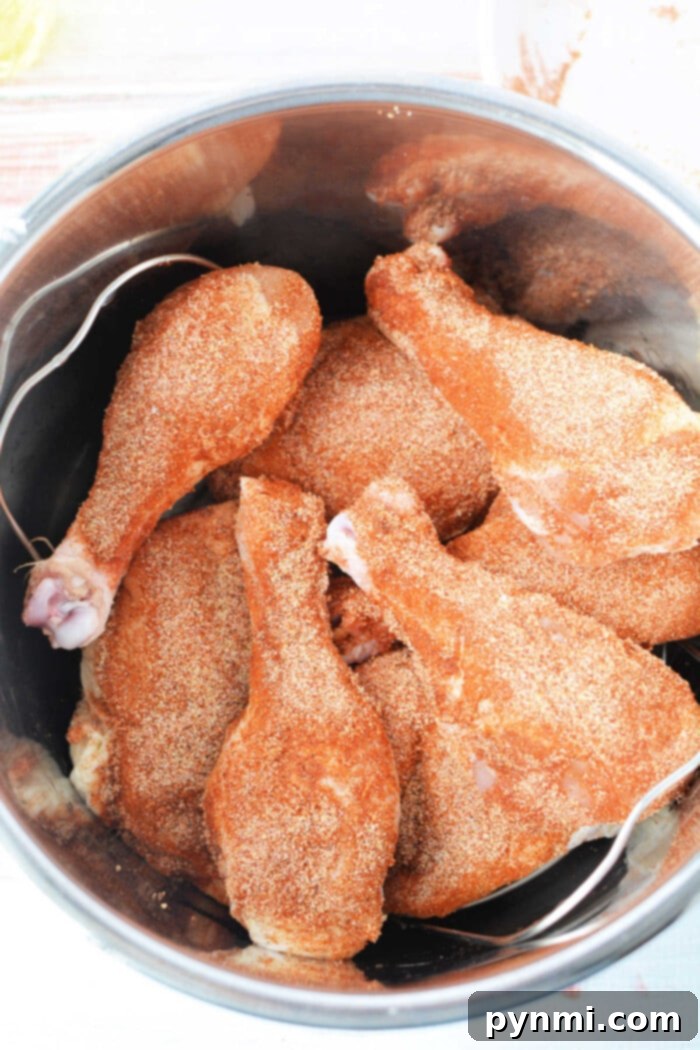 Chicken drumsticks, expertly seasoned and nestled in a metal pot, are transformed into succulent fried chicken using the magic of a pressure cooker.