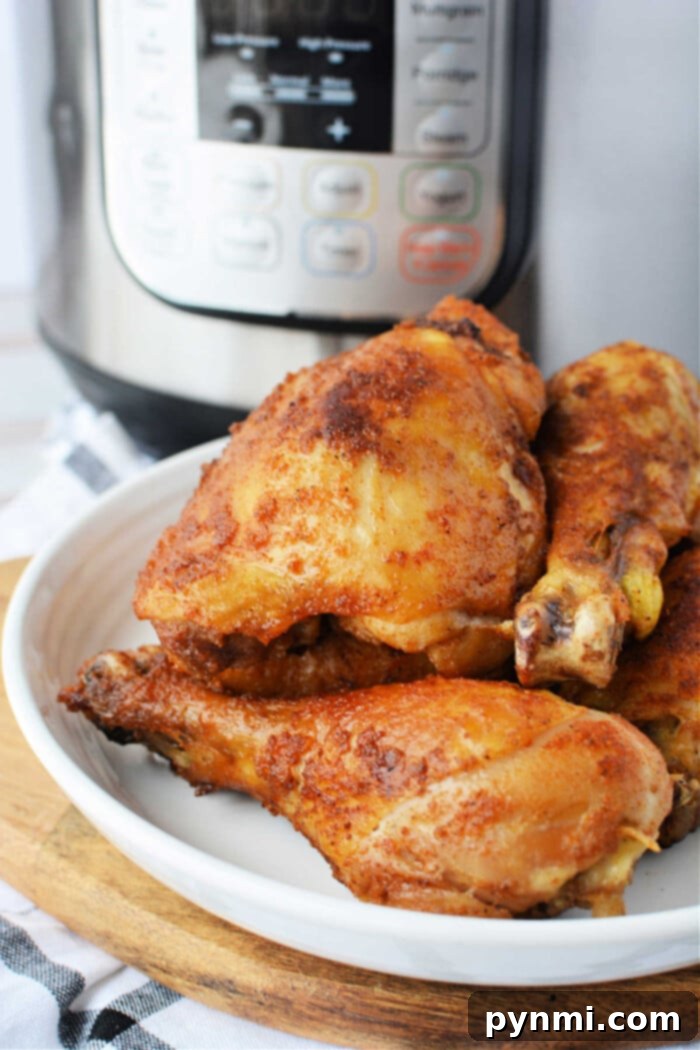 Cooked, seasoned chicken drumsticks rest enticingly on a white plate in front of an Instant Pot, offering a glimpse into the world of pressure cooker marvels.