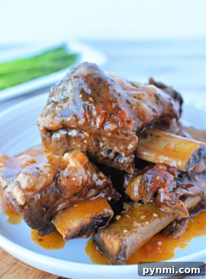 Close-up of a plate featuring mouthwatering braised beef short ribs, simmered to perfection in a pressure cooker and garnished with a rich red sauce, all elegantly presented on a white plate.